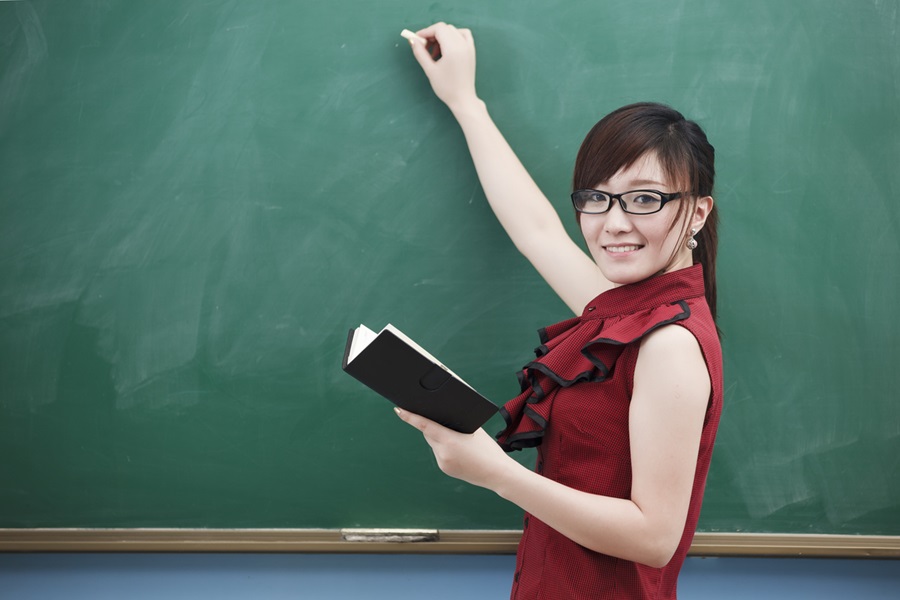 Smiling teacher writing on the blackboard